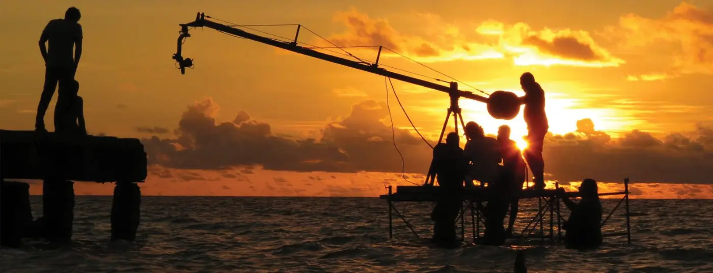 Film crew with a camera crane at sunset on the set of Haadharu